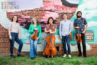 musicians standing in front of a mural
